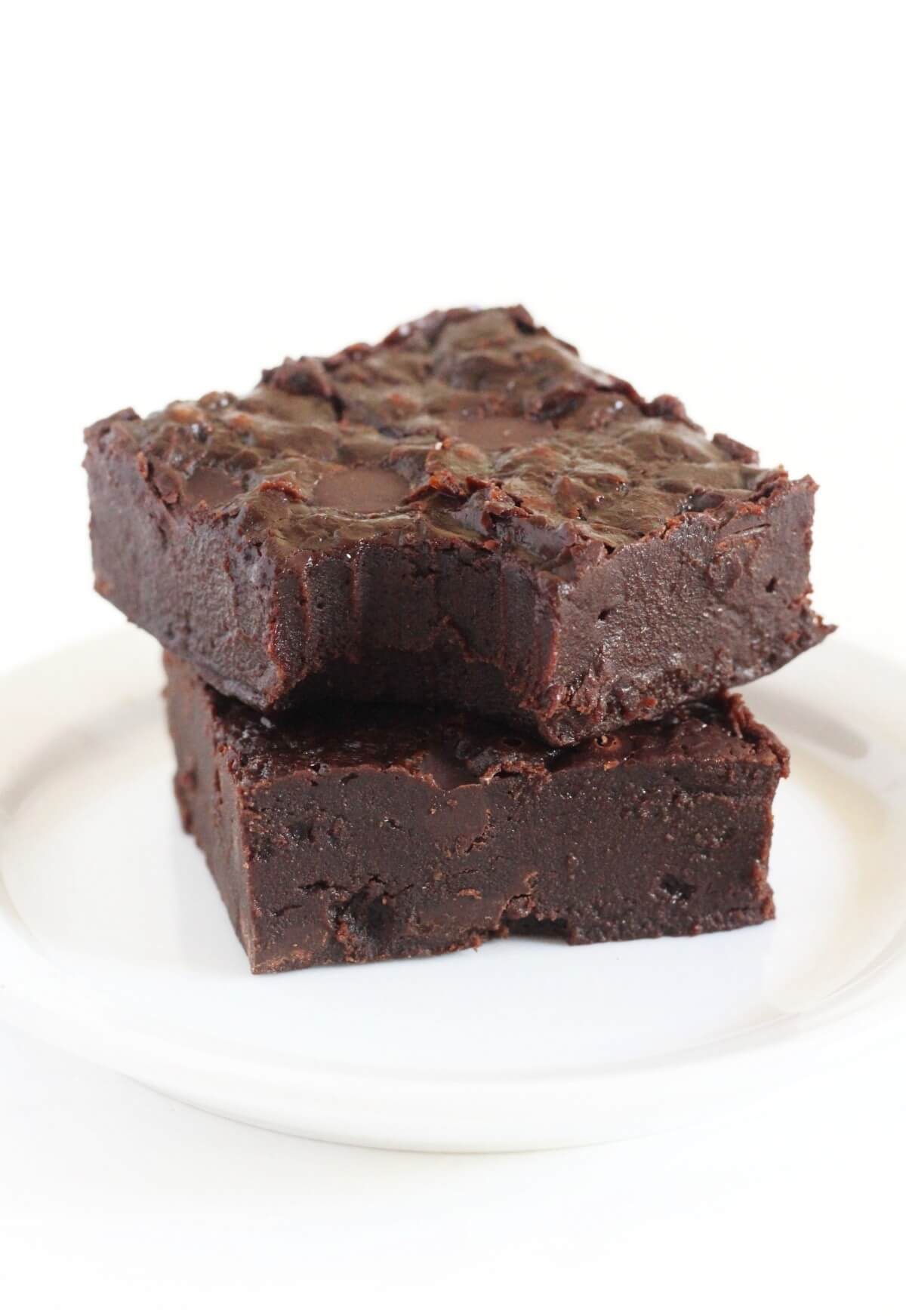 two stacked fudgy vegan brownies on plate.