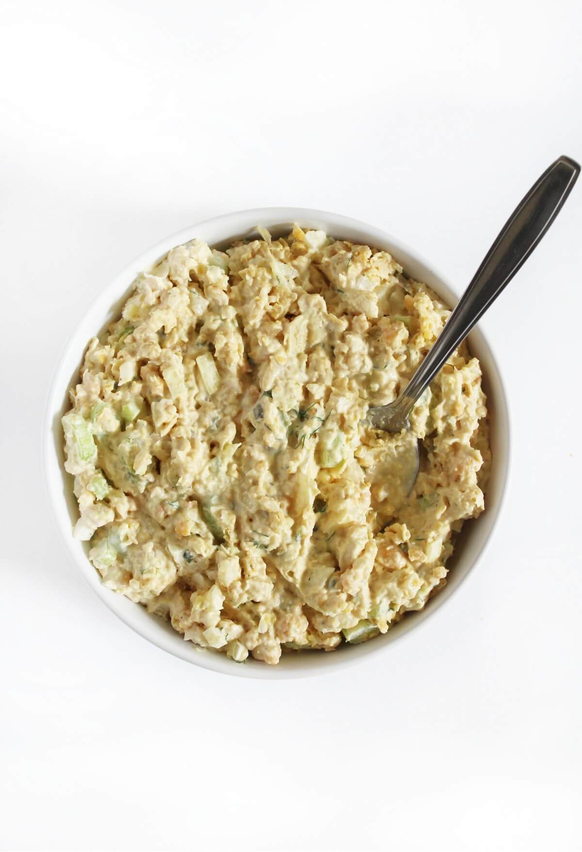 overhead view of vegan chickpea tuna salad in serving bowl with metal spoon.
