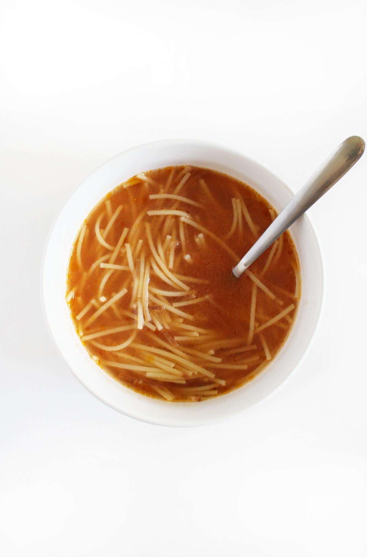 plain bowl of vegan sopa de fideo with spoon.