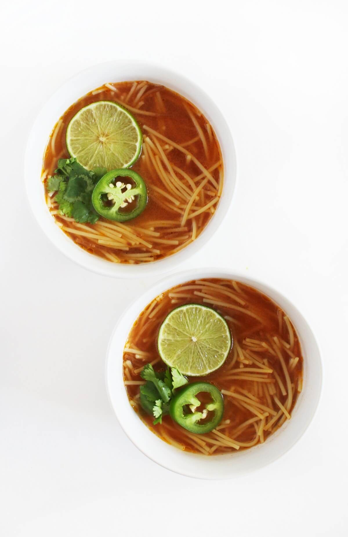 two bowls of gluten-free sopa de fideo with toppings.