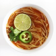 single white bowl of vegan sopa de fideo with lime, jalapeno, cilantro.