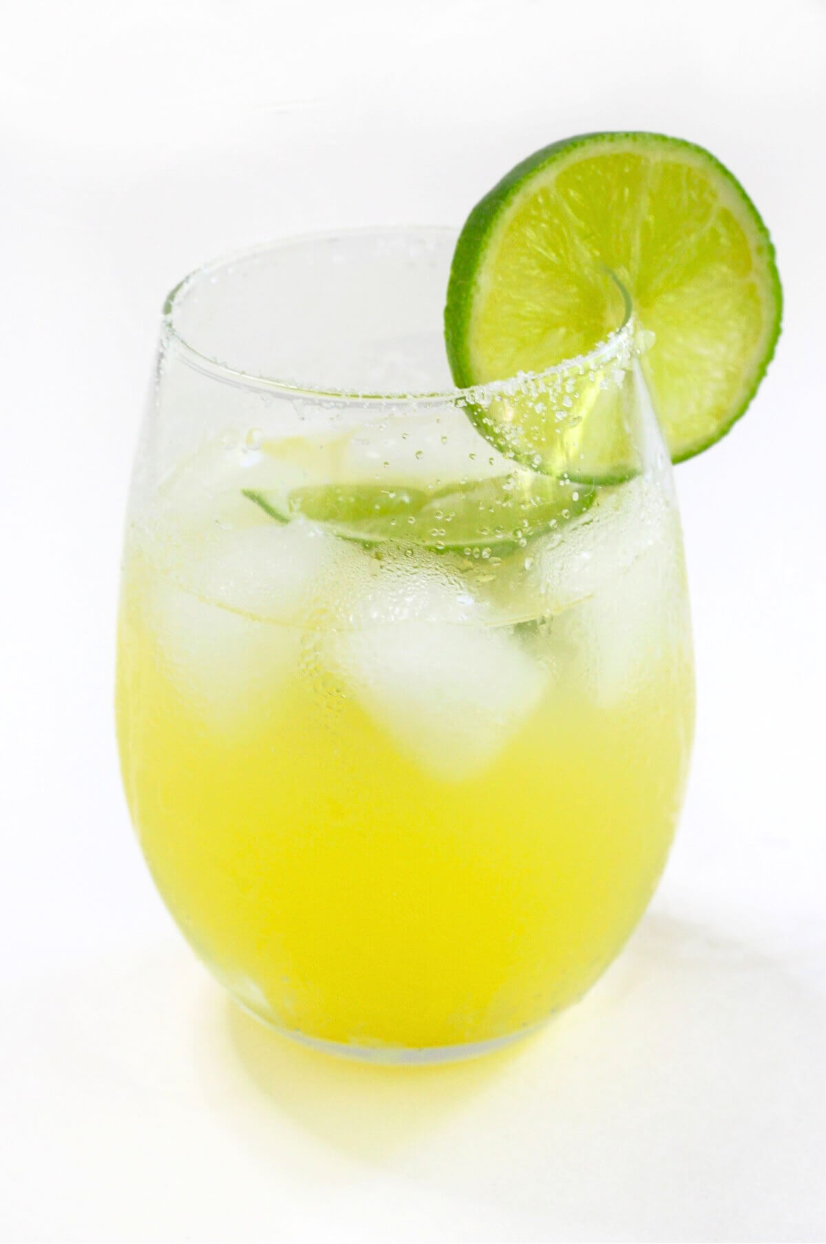 single finished glass of non-alcoholic margarita with lime wedges.
