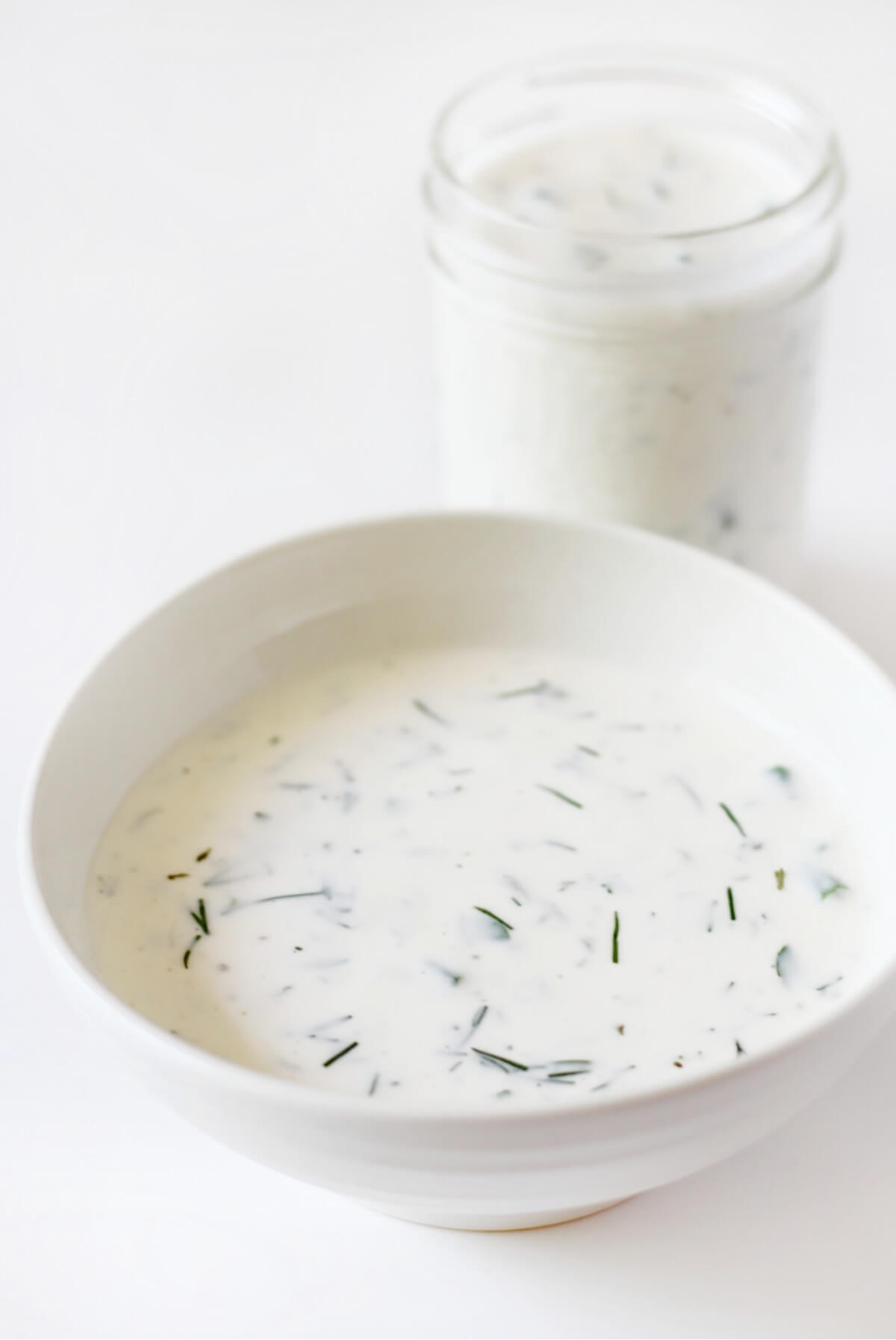 bowl of vegan ranch dressing and glass jar with more.