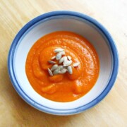 single bowl of roasted butternut squash carrot soup with butternut squash seeds topping.