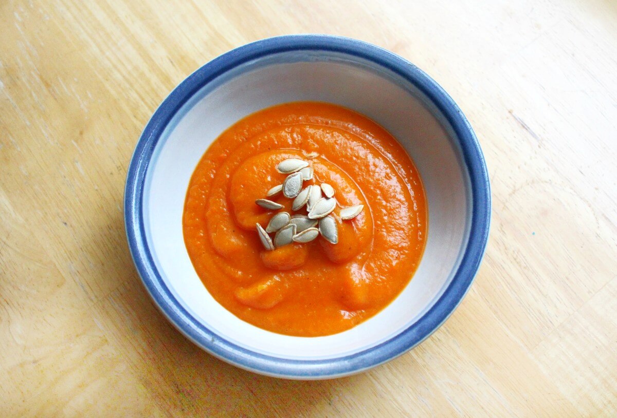 single bowl of roasted butternut squash carrot soup with butternut squash seeds topping.