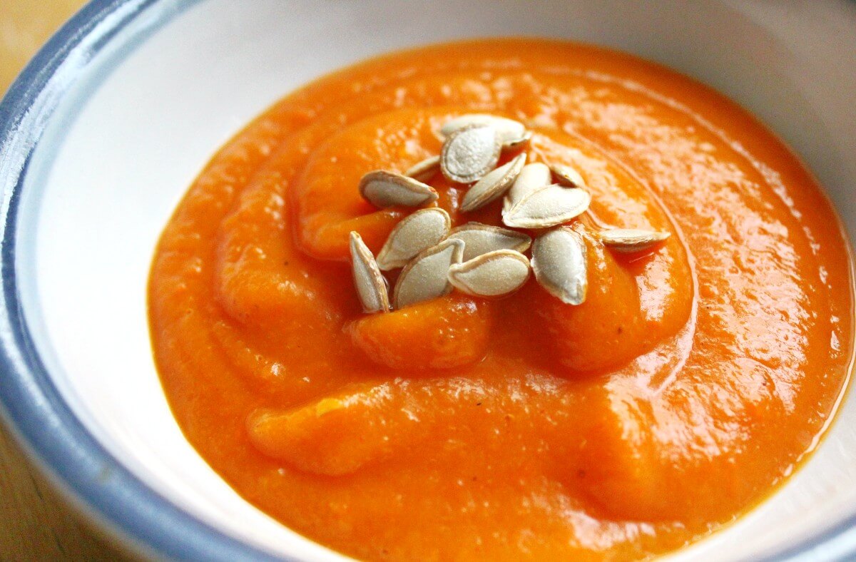 close-up of bowl of butternut squash carrot soup with roasted seeds.