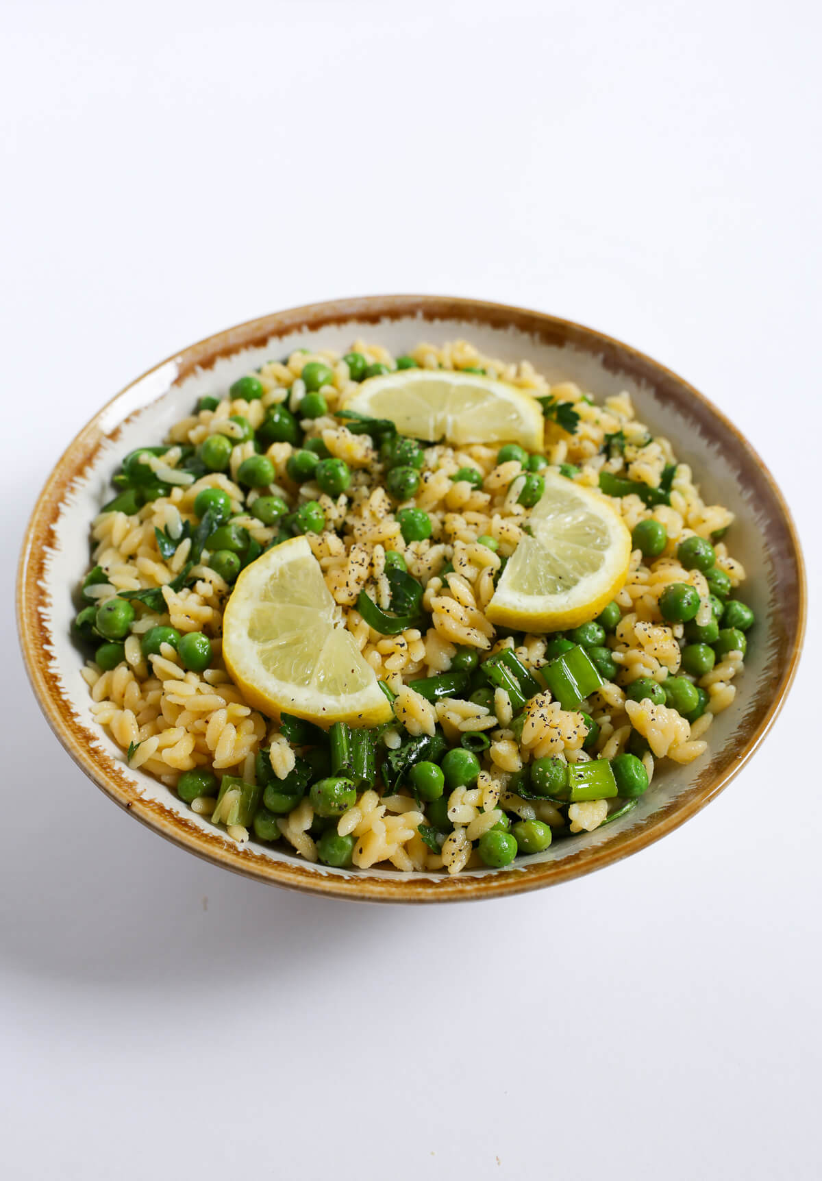 bowl of gluten-free vegan spring pasta salad with lemon slices.