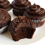 bitten into gluten-free vegan chocolate cupcake on plate.
