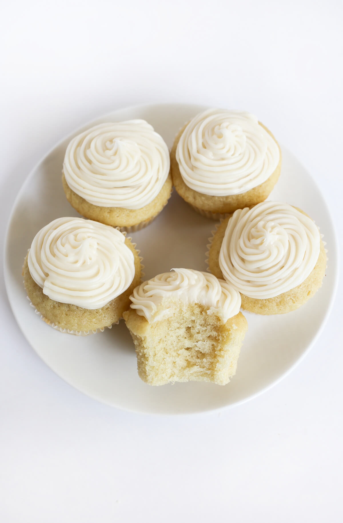 gluten-free vegan vanilla cupcakes bitten into on plate.