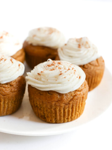 gluten-free pumpkin cupcakes with vegan cream cheese frosting on plate.