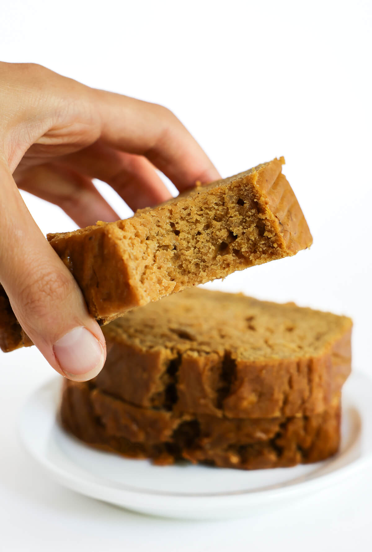 hand grabbing a slice of gluten-free pumpkin banana bread.