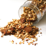 apple cinnamon granola spilled out of glass jar.
