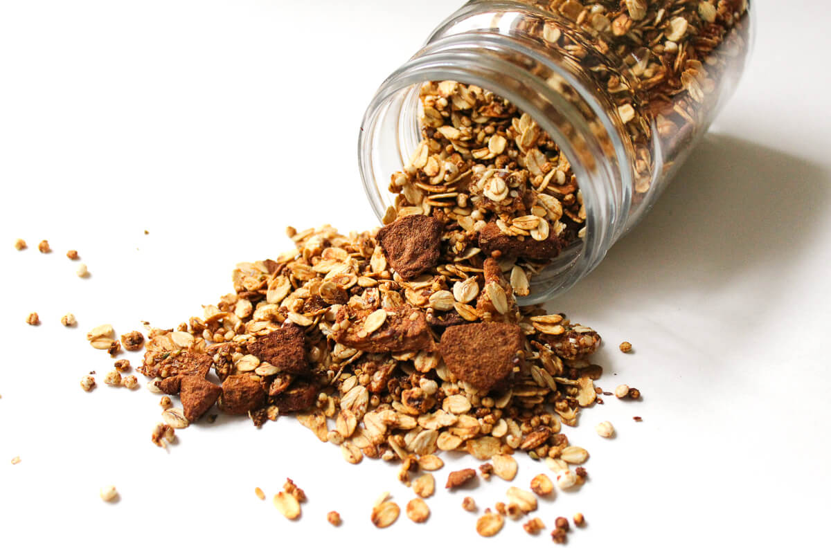 apple cinnamon granola spilled out of glass jar.