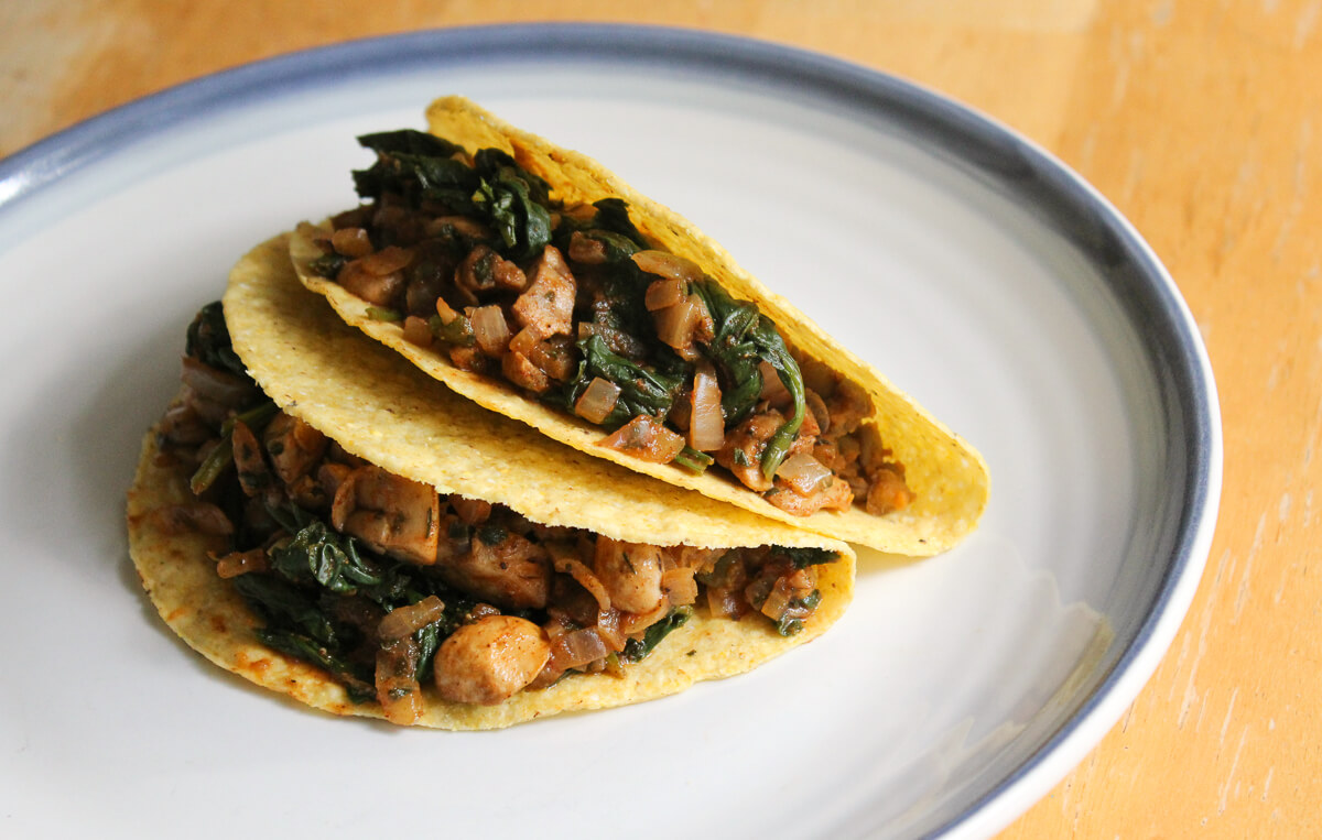 two pumpkin lentil tacos in corn shells on plate.
