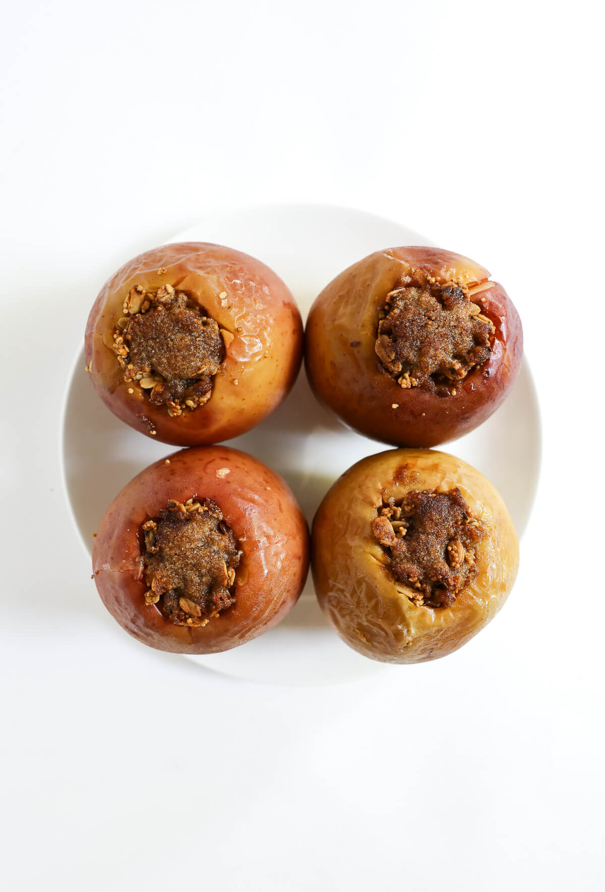 four stuffed baked apples on plate with crisp brown sugar topping.