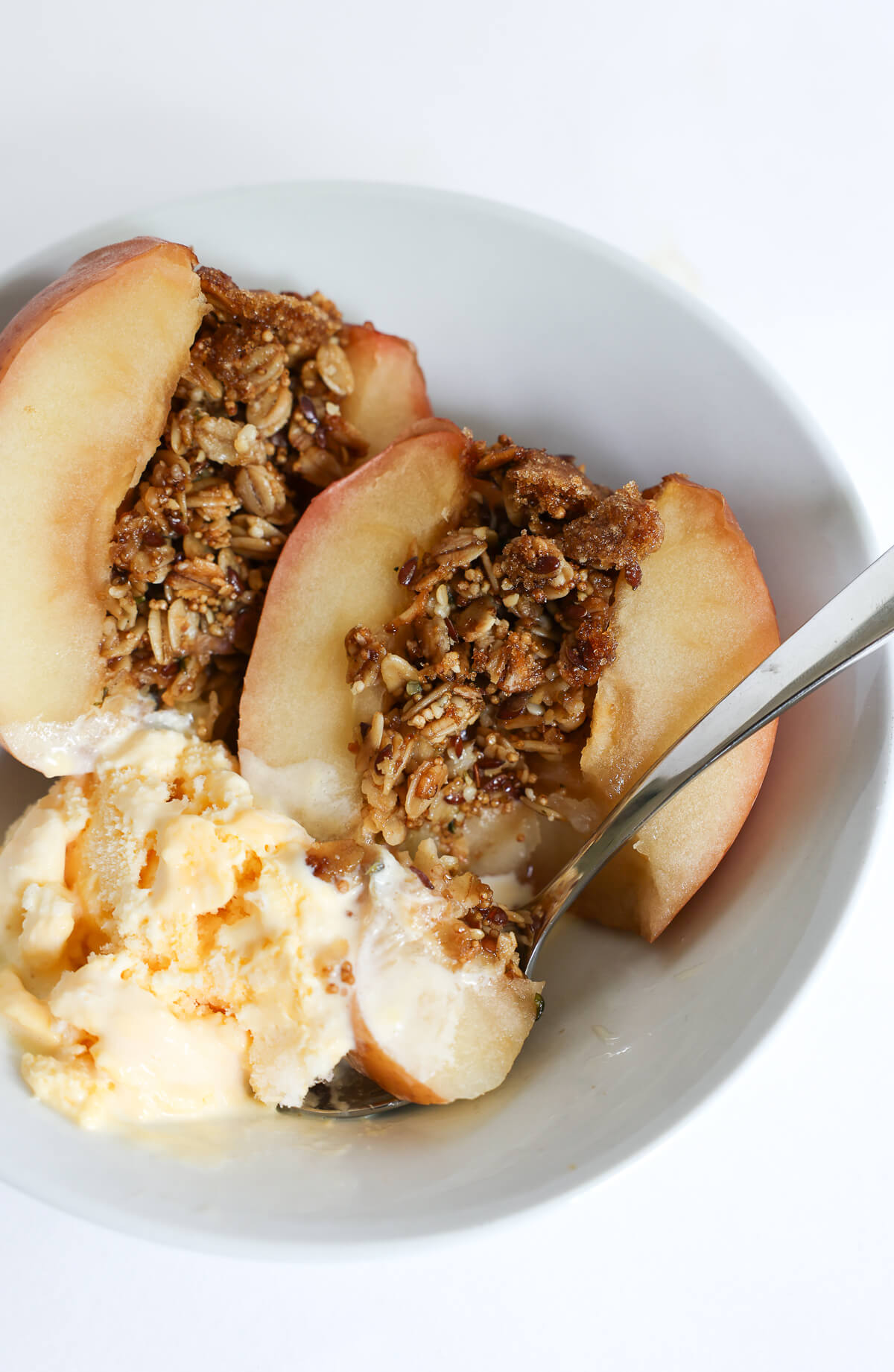 close up of stuffed baked apples with granola and vanilla ice cream.