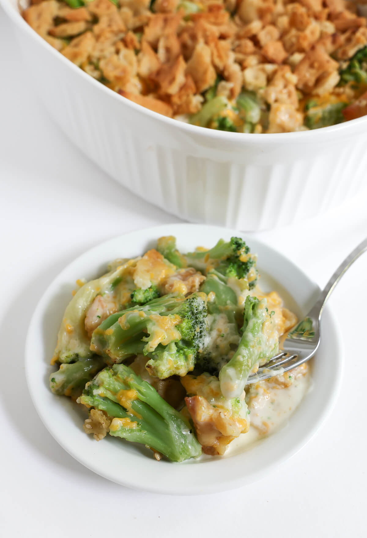 plate of vegan broccoli casserole with full casserole in background.
