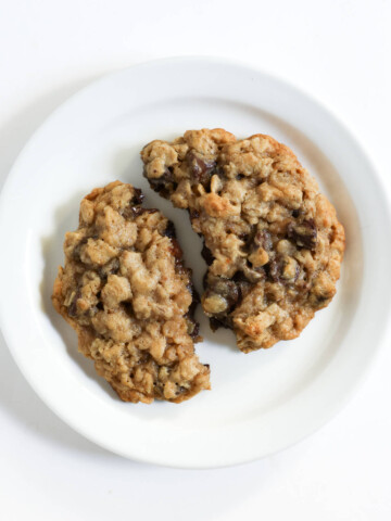 one large gluten-free oatmeal chocolate chip cookie on plate broken in half.