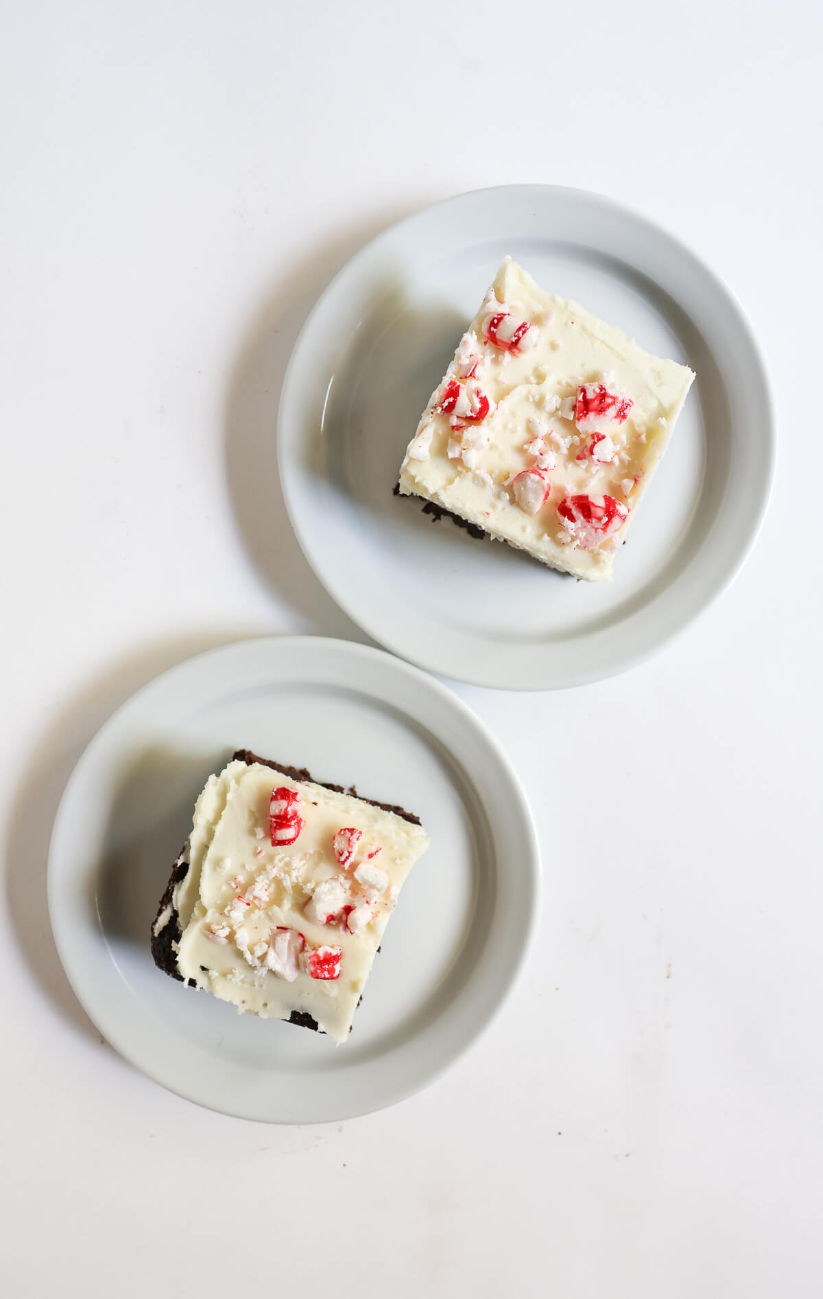 overhead view of two peppermint bark brownies on plates.