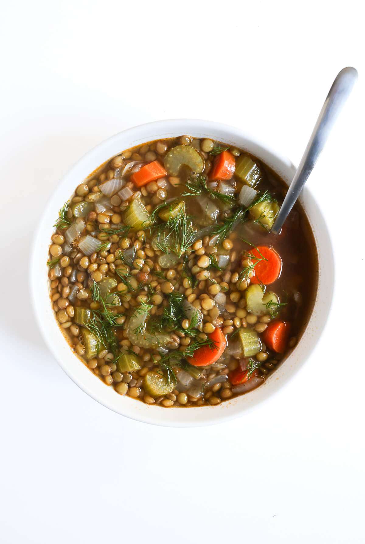 traditional lentil soup in white bowl with spoon to eat.