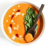 bowl of vegan thai carrot soup with wooden spoon scoop.