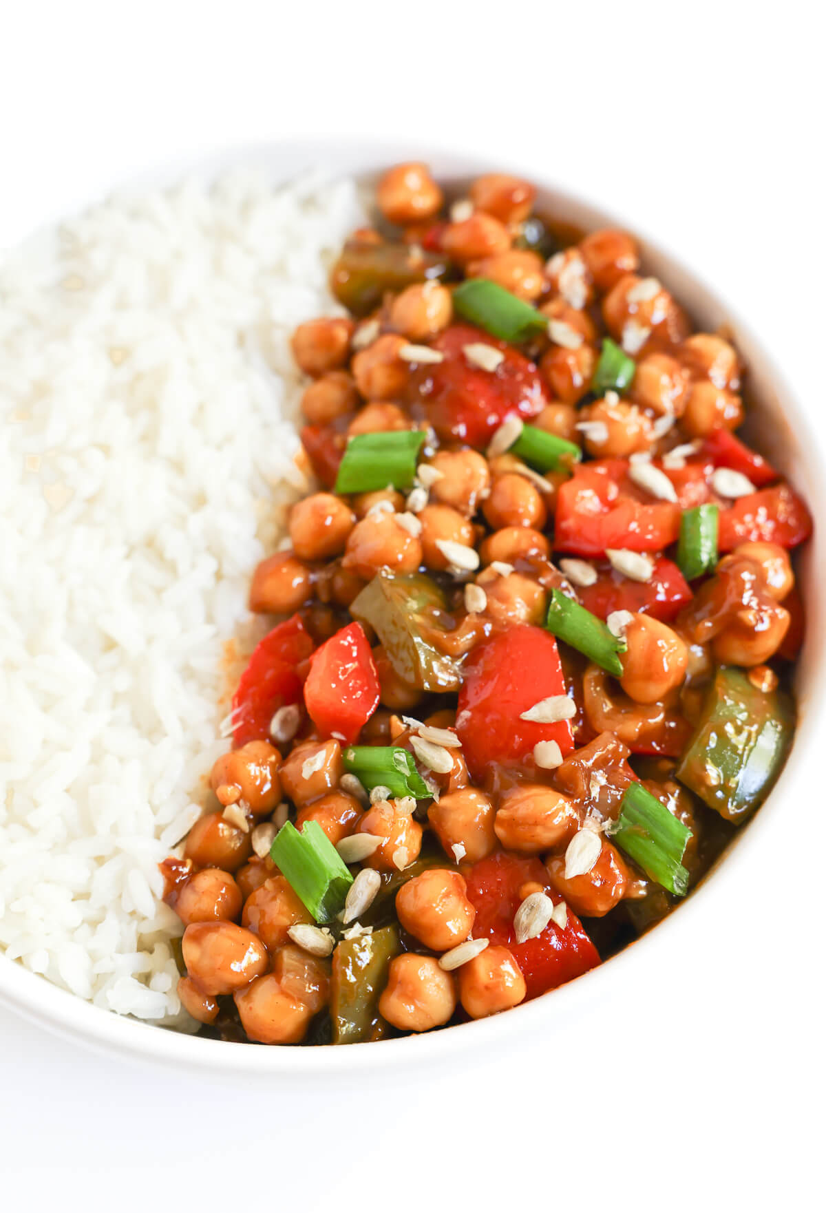 close up of vegan kung pao chickpeas in white bowl with rice.