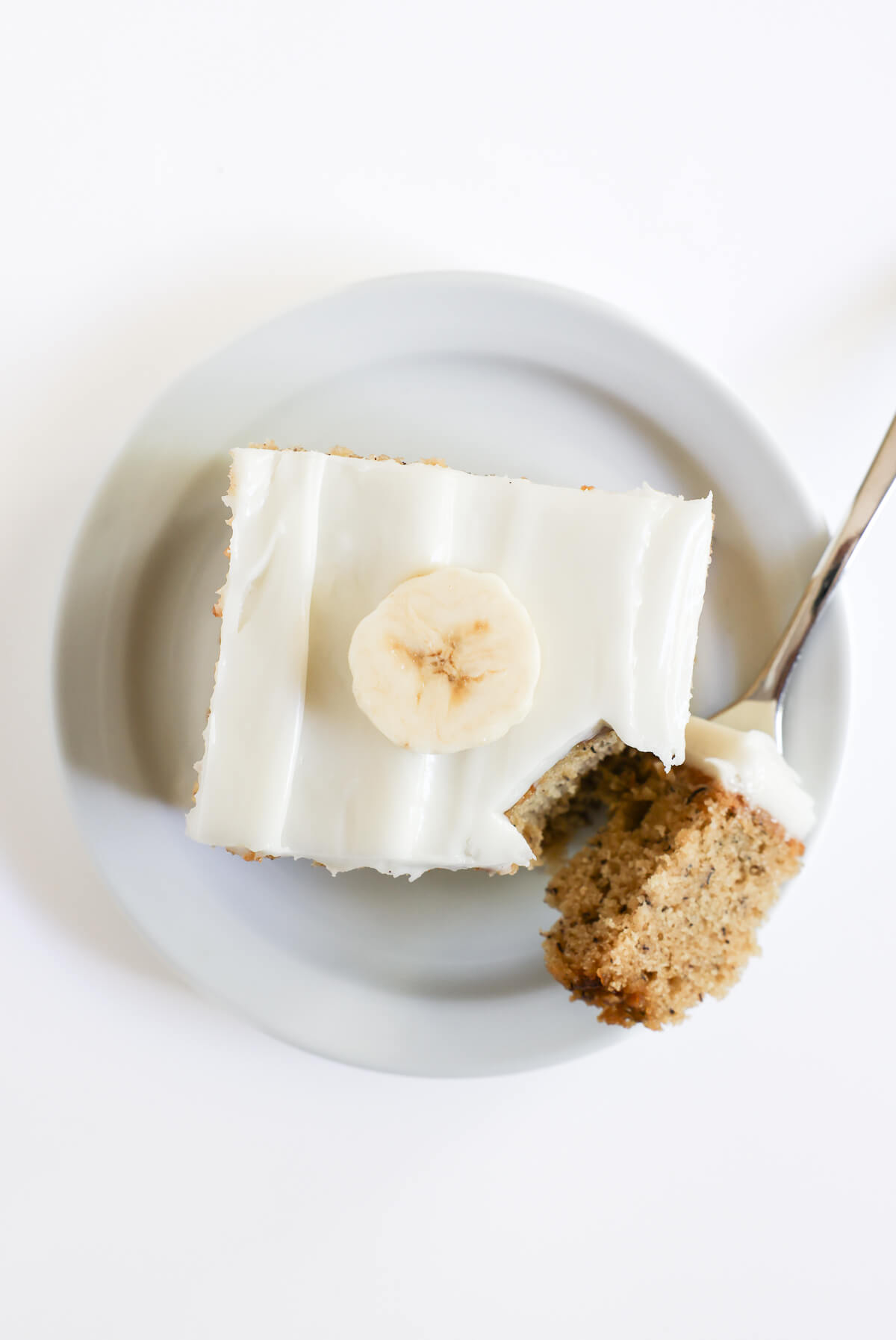 overhead view of sliced gluten-free banana cake with vegan cream cheese frosting.