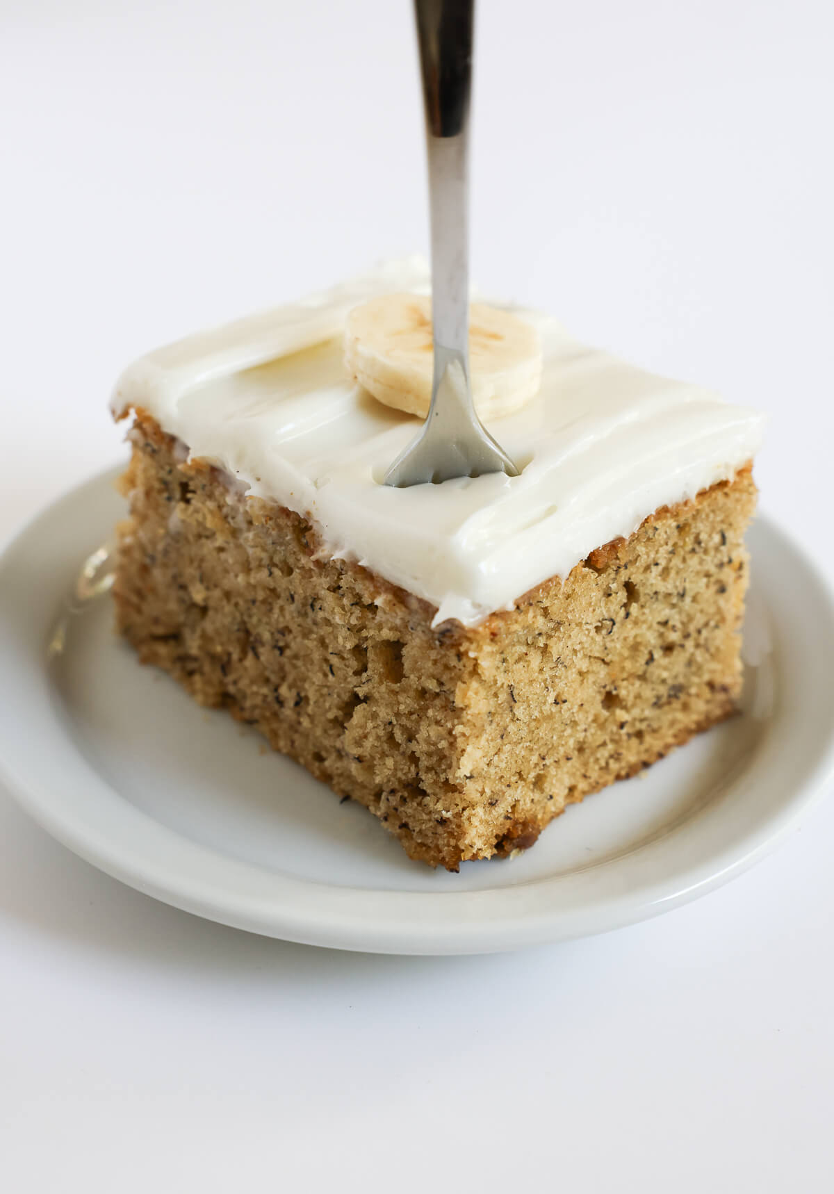 square slice of gluten-free vegan banana cake with fork poked in.