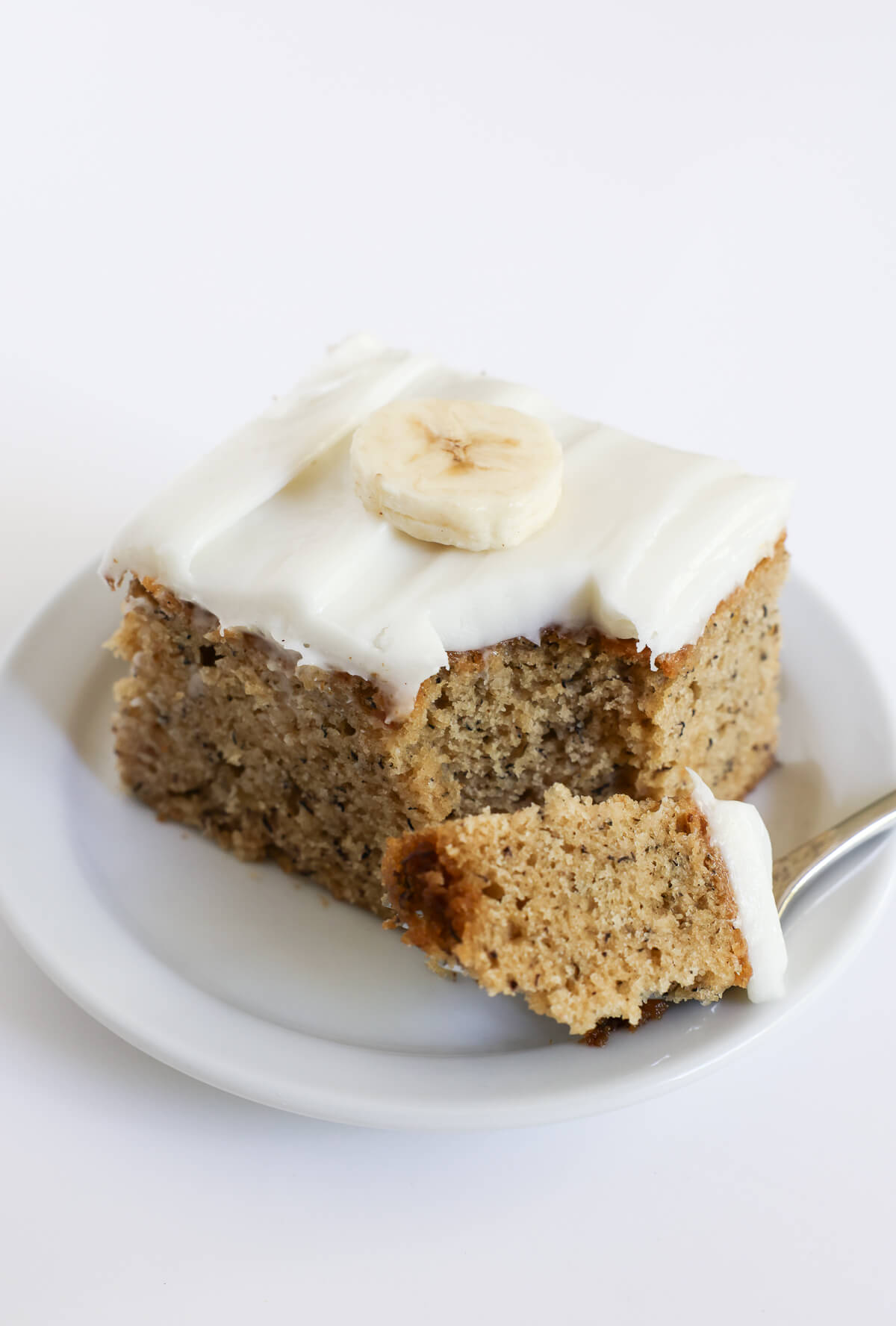 forkful of vegan banana cake with cream cheese frosting.