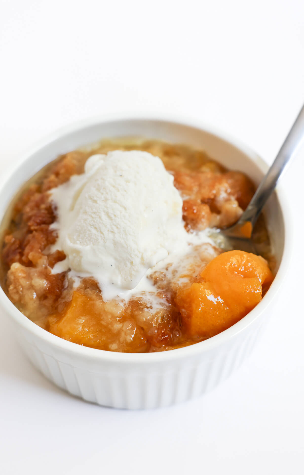 serving of gluten-free peach dump cake with vegan ice cream.