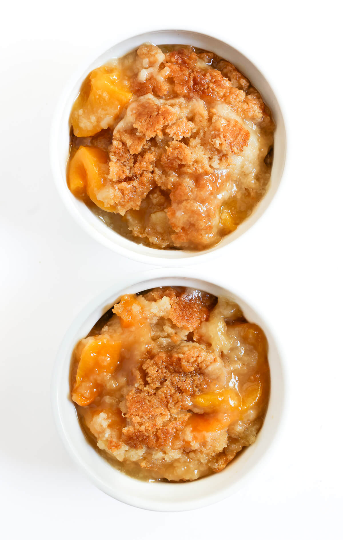 two individual ramekins portions with vegan peach dump cake.