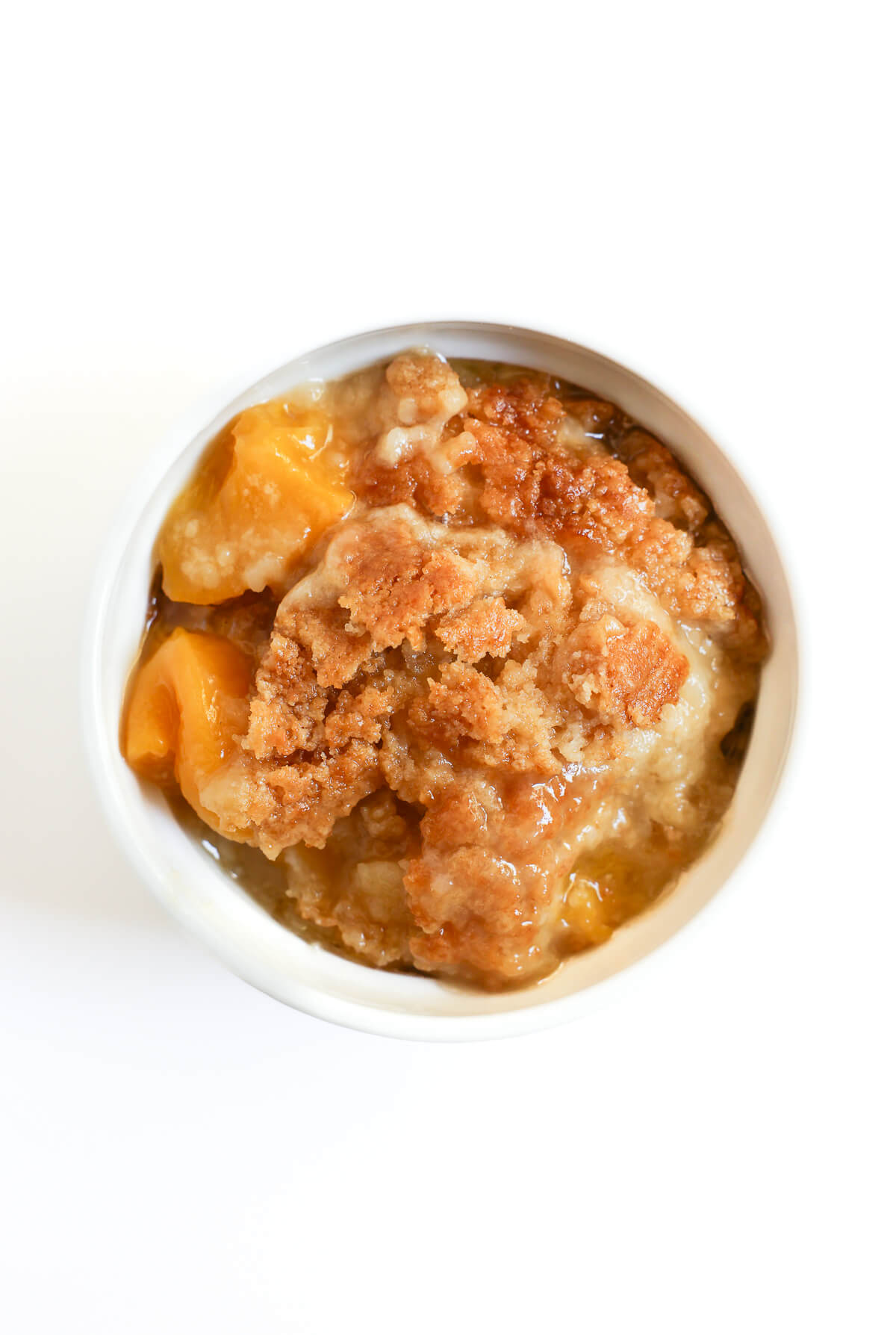 easy peach dump cake serving in white ramekin.